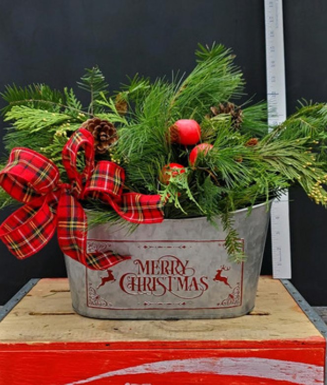 Option #2 Oval shaped tin with the words, "Merry Christmas" in red on the container with a reindeer sillouhette on each side. The tin is stuffed with various evergreens, berries, holiday bulbs, and a red ribbon. $45